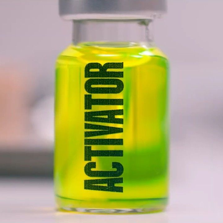 the bottle is full of green liquid with black letters on it, and has a silver cap