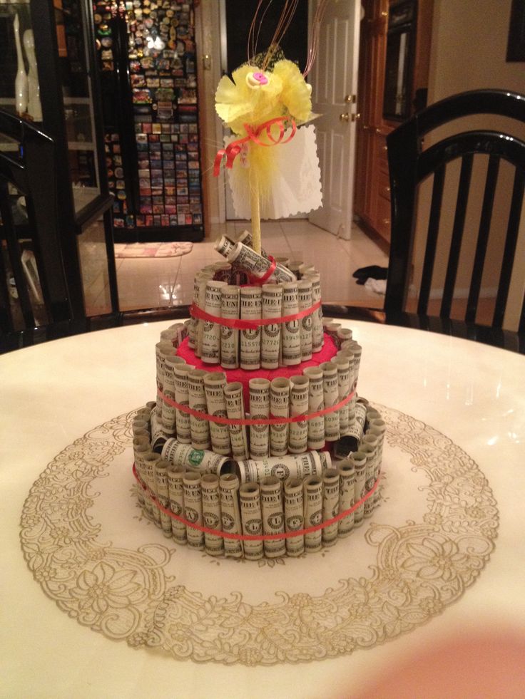 a cake made out of money sitting on top of a table in a room with chairs