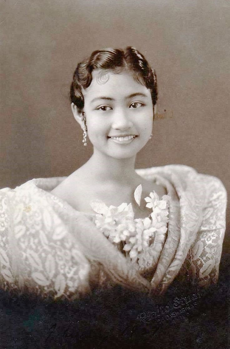 an old black and white photo of a woman wearing a dress with flowers on it