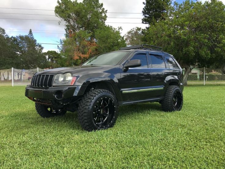 a black jeep parked on top of a lush green field