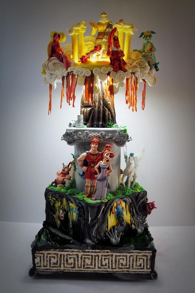 an elaborately decorated cake with figurines on it's sides and lights in the background