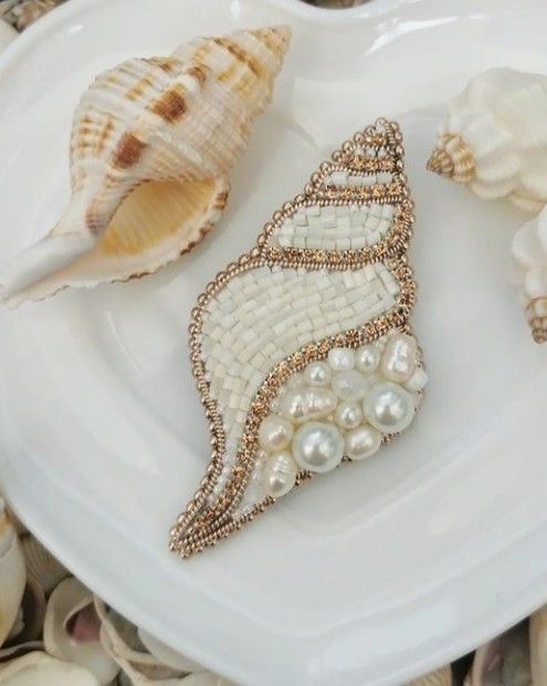 three seashells are on a white plate with pearls and other sea shells around them