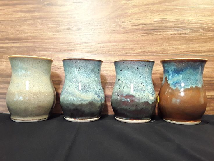 four different colored vases lined up on a table