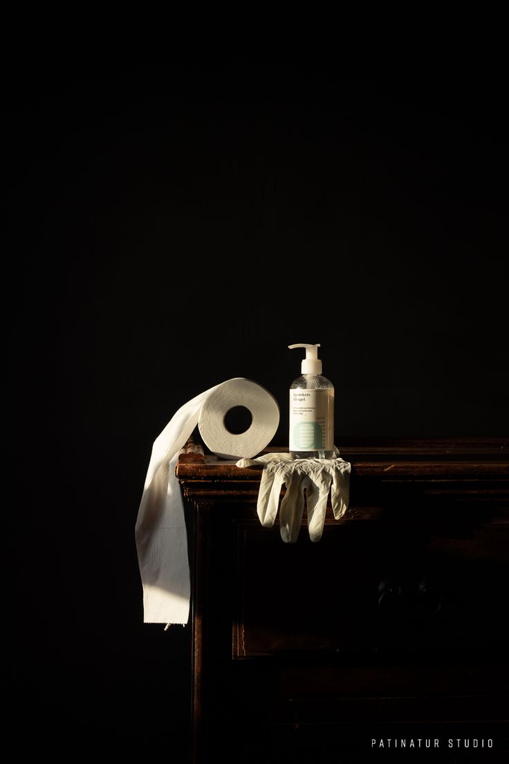 a soap dispenser sitting on top of a wooden table next to a white cloth