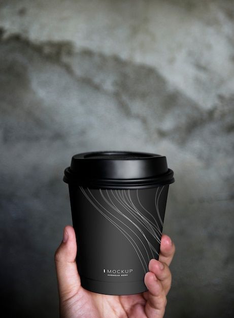 a person holding up a black coffee cup