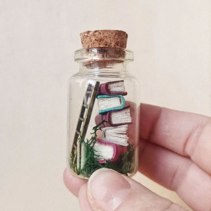 a hand holding a glass bottle filled with books