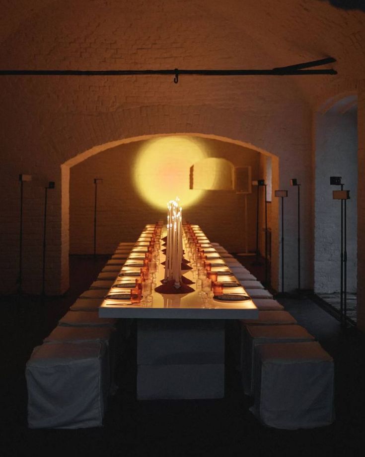 a long table with candles on it in a dimly lit room under a light fixture