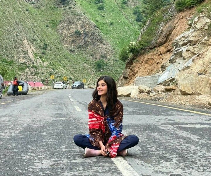 a woman sitting on the side of a road