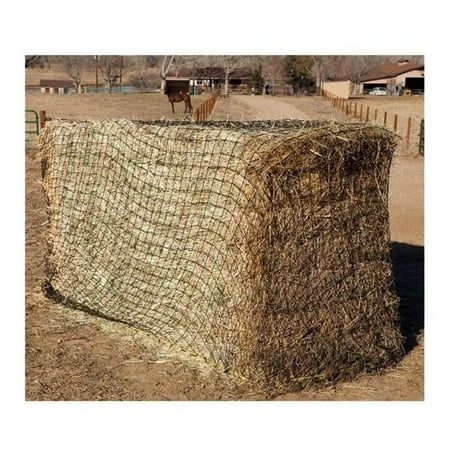 a horse standing on top of a hay bale in the middle of a field