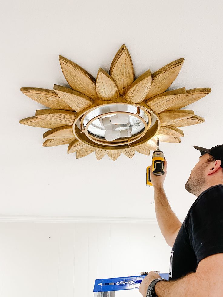 a man using a drill to fix a light fixture