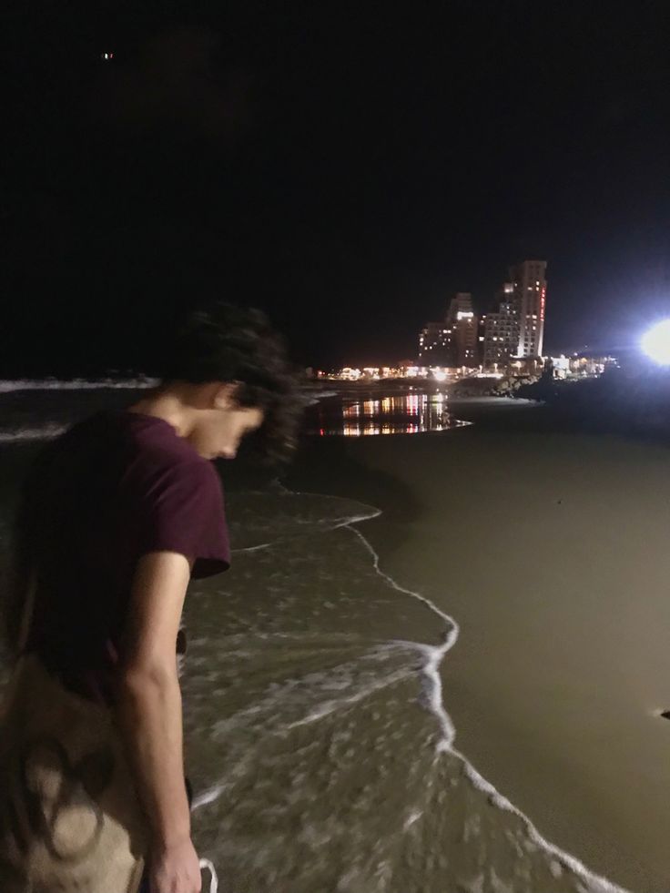 a man standing on top of a beach next to the ocean