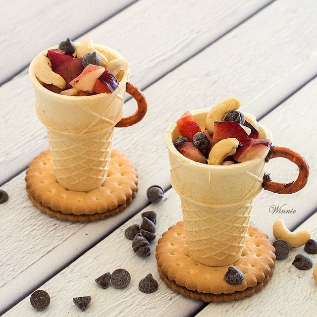 two ice cream cones filled with fruit and chocolate chips on top of a wooden table