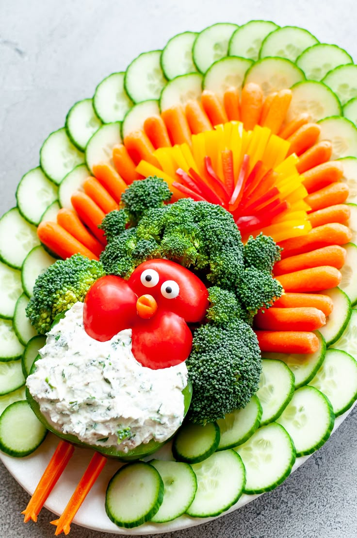 a plate filled with cucumbers, carrots and broccoli topped with a chicken