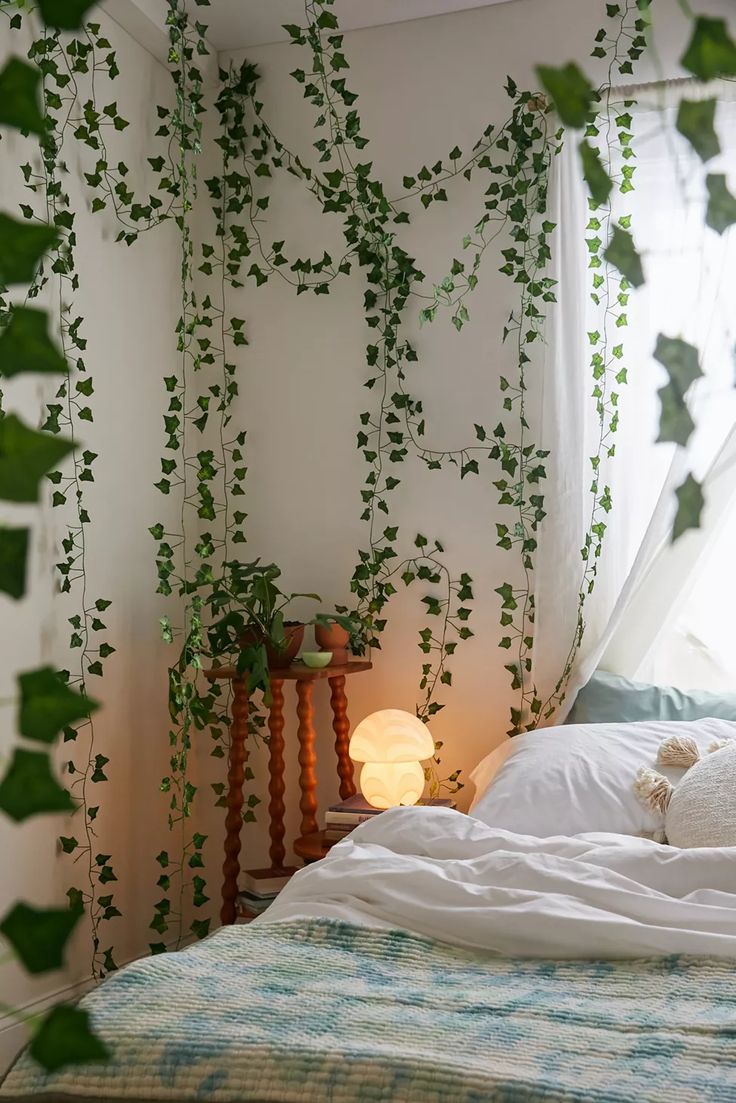 a bed with white sheets and green plants on the wall