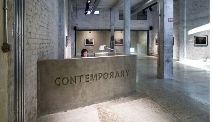 the entrance to an art gallery with stone walls and concrete pillars that read, contemporary contemporary contemporary