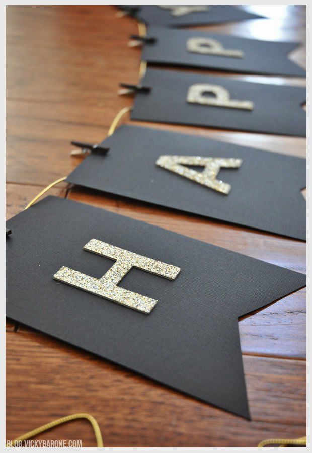 black and gold banner with glitter letters on it sitting on a wooden table in front of a wood floor