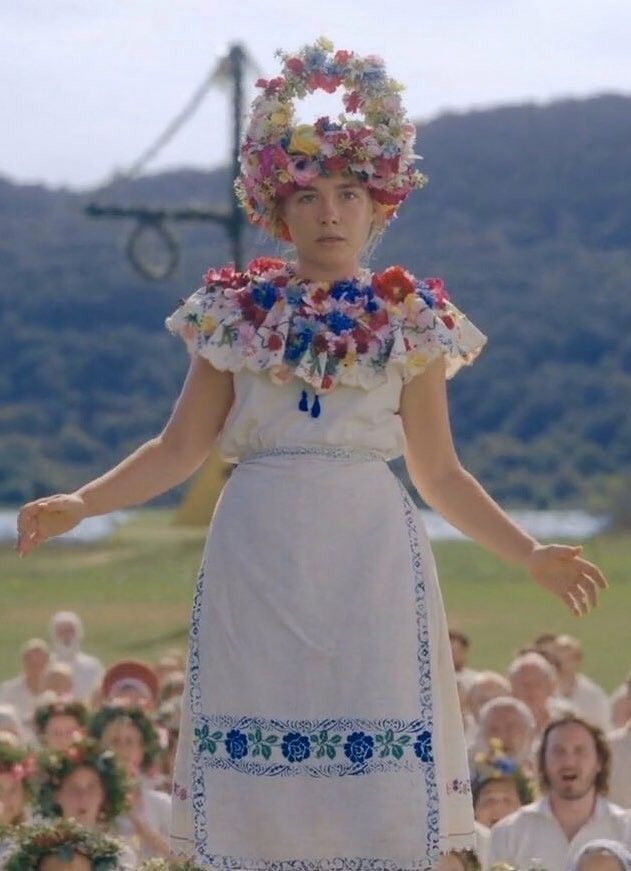 a woman standing on top of a lush green field next to a bunch of people