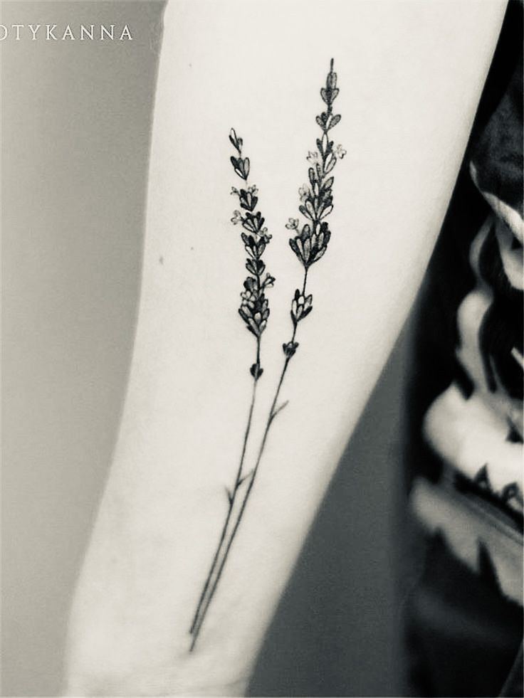 a black and white photo of two lavender flowers on the left inner arm tattoo design