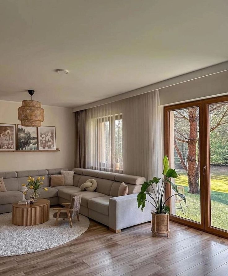 a living room filled with furniture next to a large glass door leading to a lush green yard