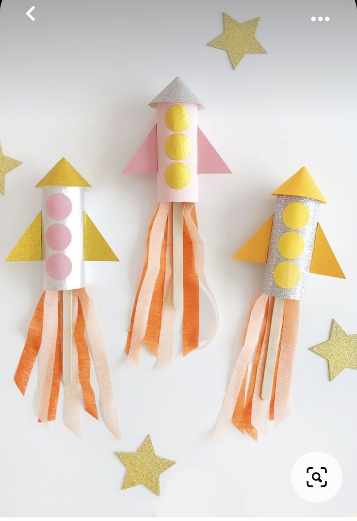 three rockets made out of construction paper on top of a white surface with stars around them