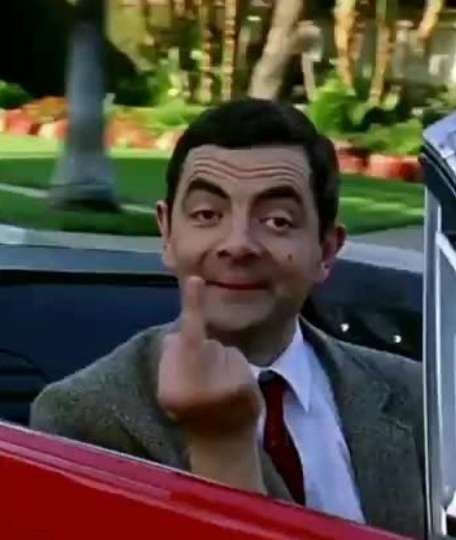 a man in a suit and tie sitting in a car with his hand on the door handle