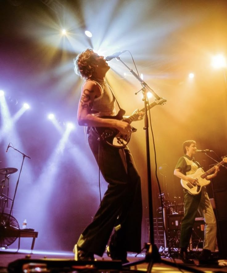 two men on stage with guitars and microphones