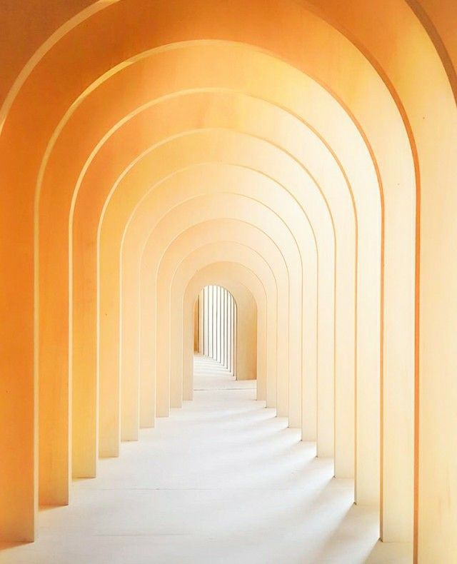 an arched hallway with white stairs leading into the light