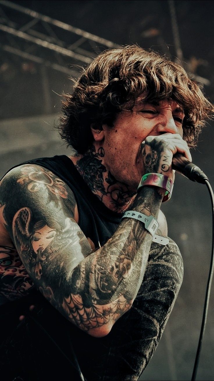 a man with tattoos on his arm singing into a microphone