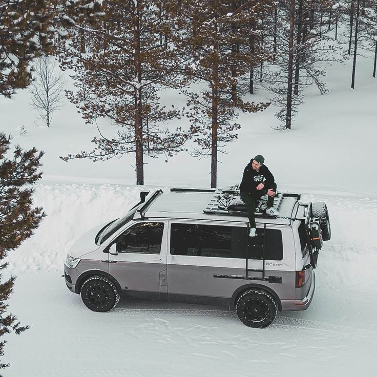 a man standing on top of a car in the snow