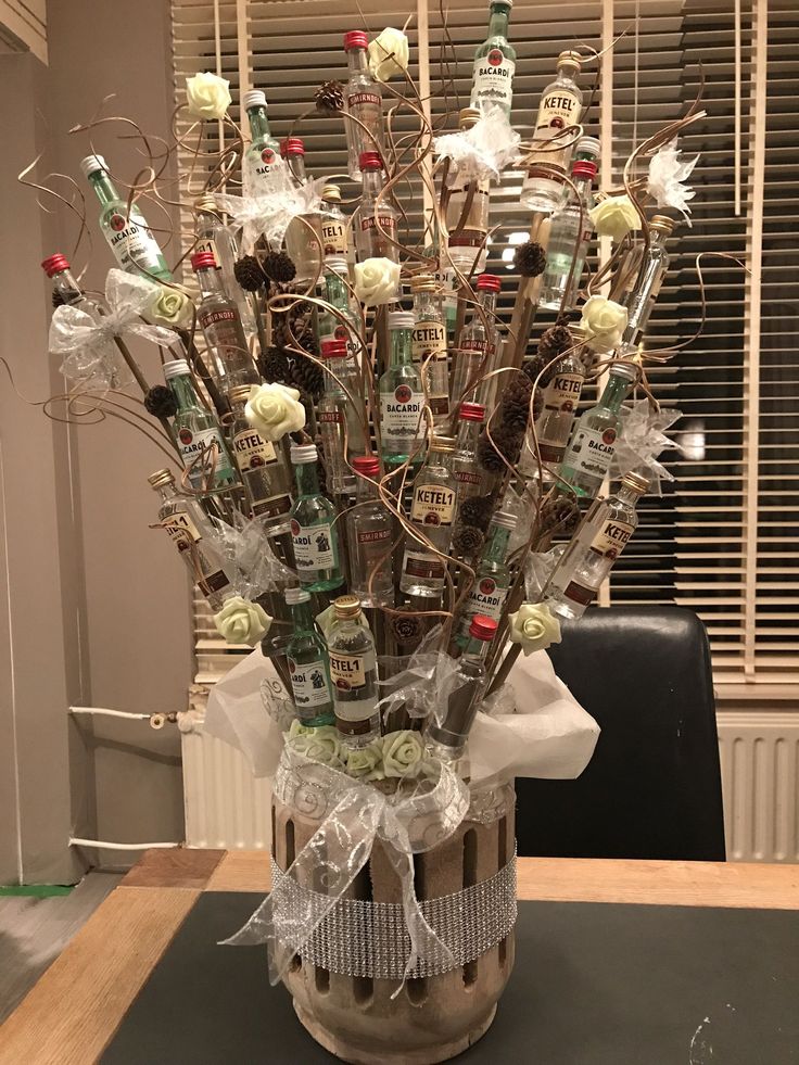 a vase filled with lots of liquor bottles on top of a table