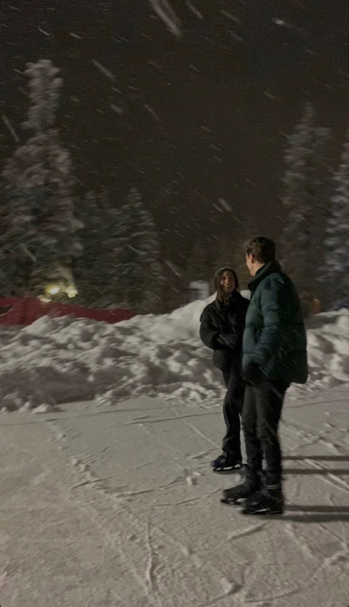 two people standing in the snow at night