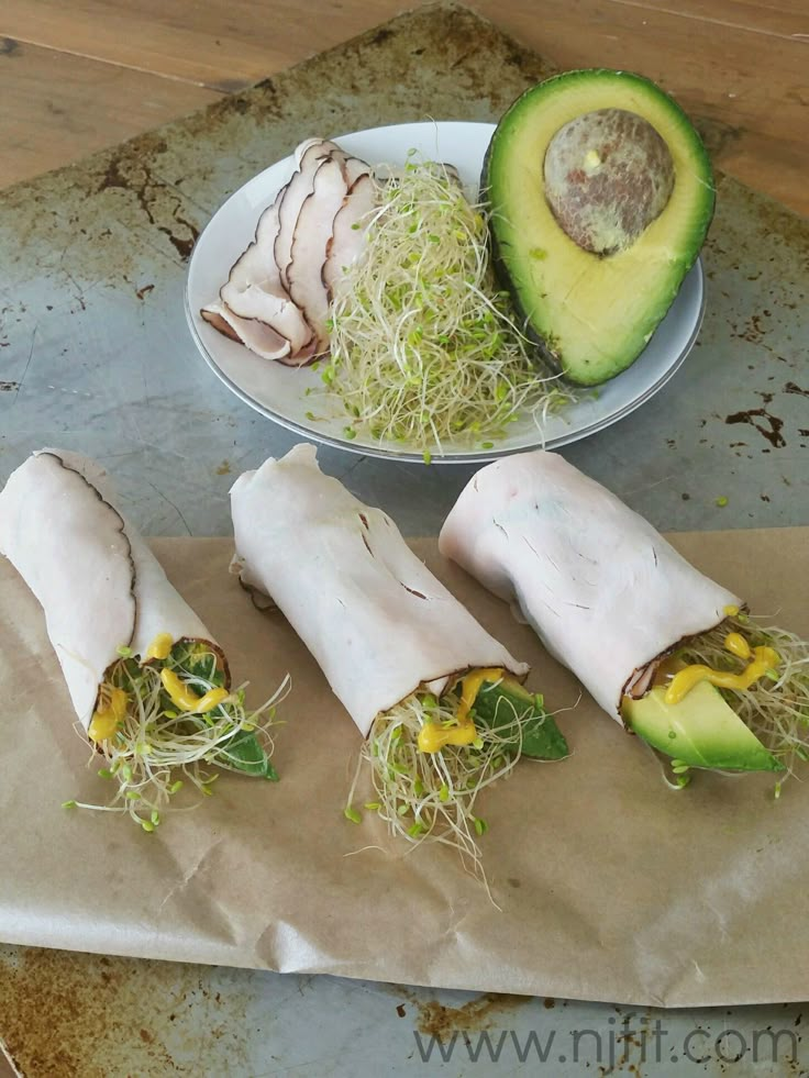 some food is laying out on a table next to a bowl and an avocado