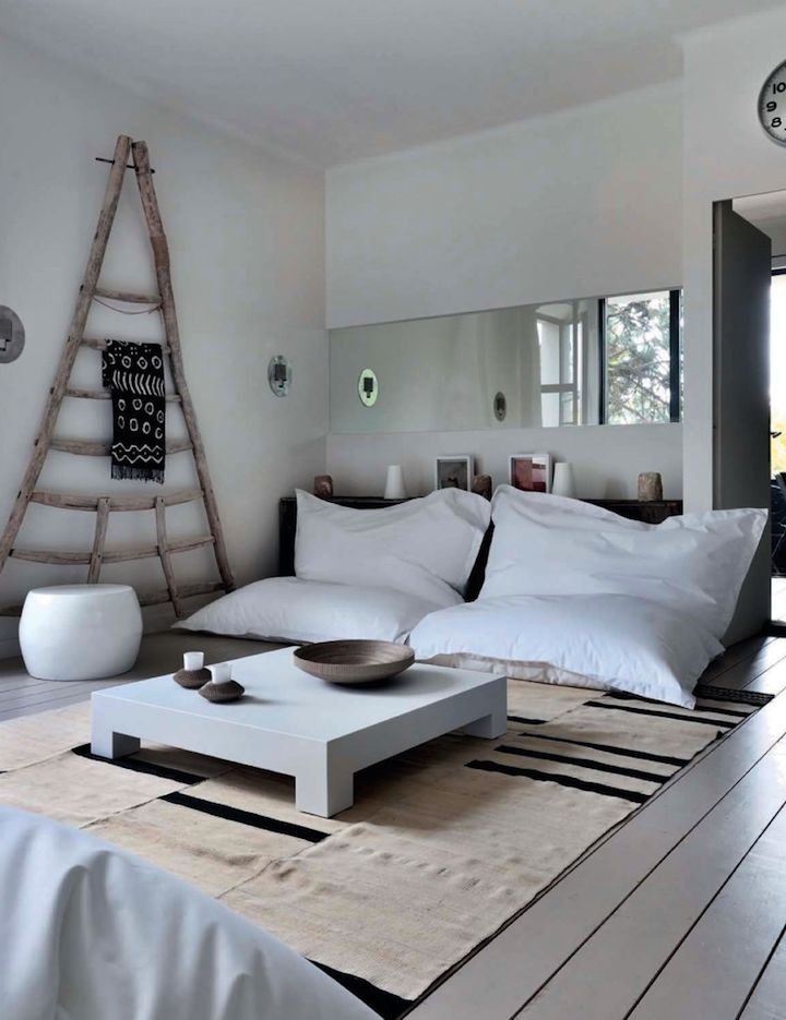 a living room filled with white furniture and pillows on top of a wooden coffee table