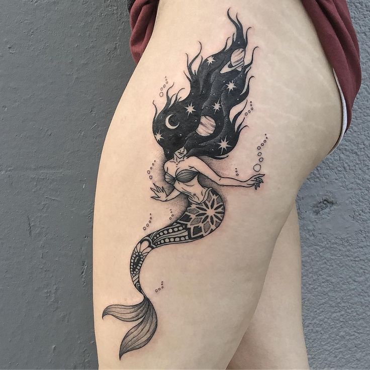 a woman's thigh with a mermaid tattoo on it