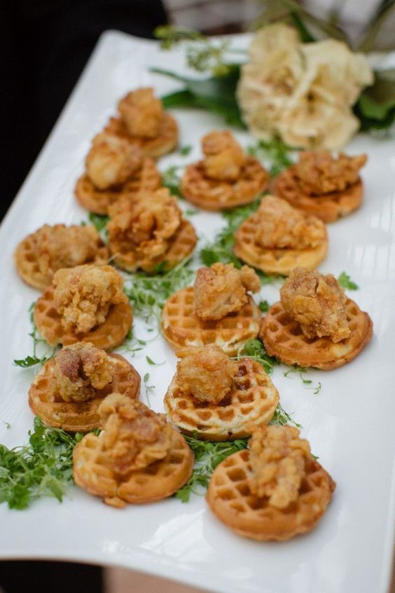 small waffles are arranged on a white platter with garnishes