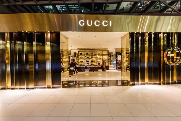 the entrance to a gucci store with people walking in and out doors that have gold foiling on them