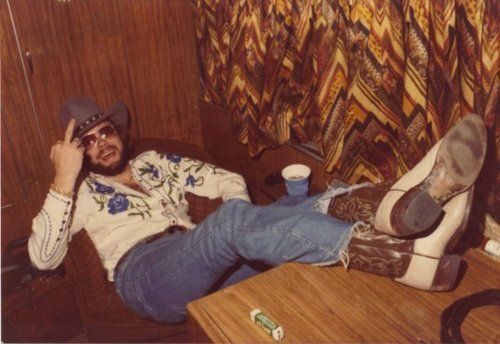 a man laying on top of a wooden table next to a pair of cowboy boots