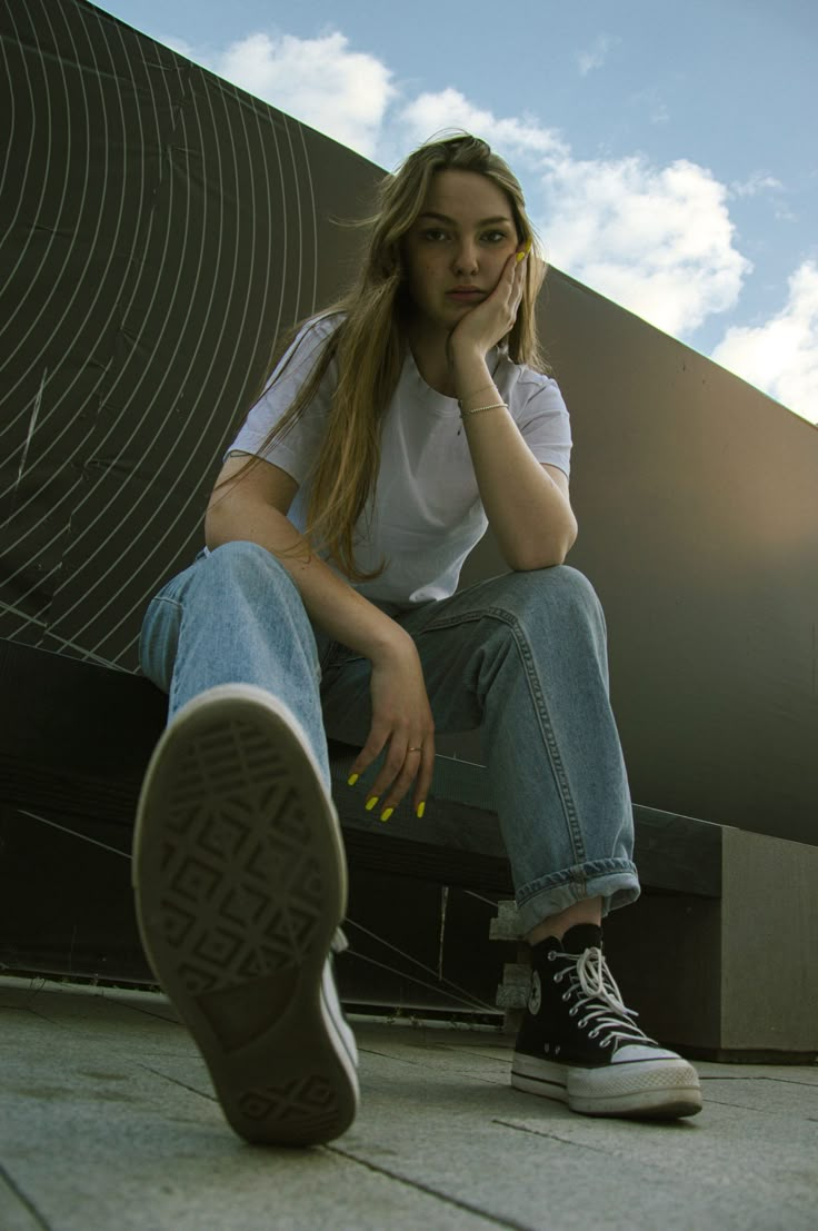 a young woman sitting on the ground with her foot up to her face and looking at the camera