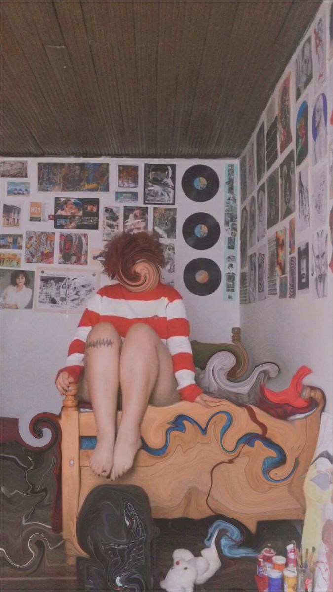 a woman sitting on top of a bed in a room filled with pictures and posters