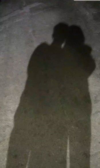 the shadow of two people standing next to each other with their arms around each other