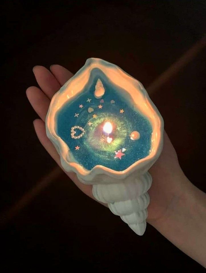 a hand holding a small candle in it's center with stars and planets on it