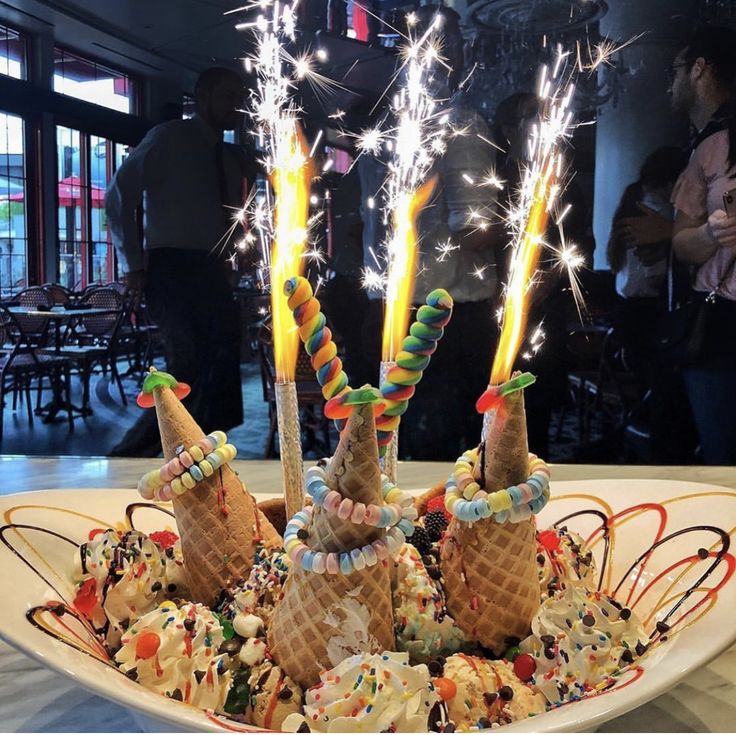 an ice cream sundae is topped with candy and sparklers in the shape of cones