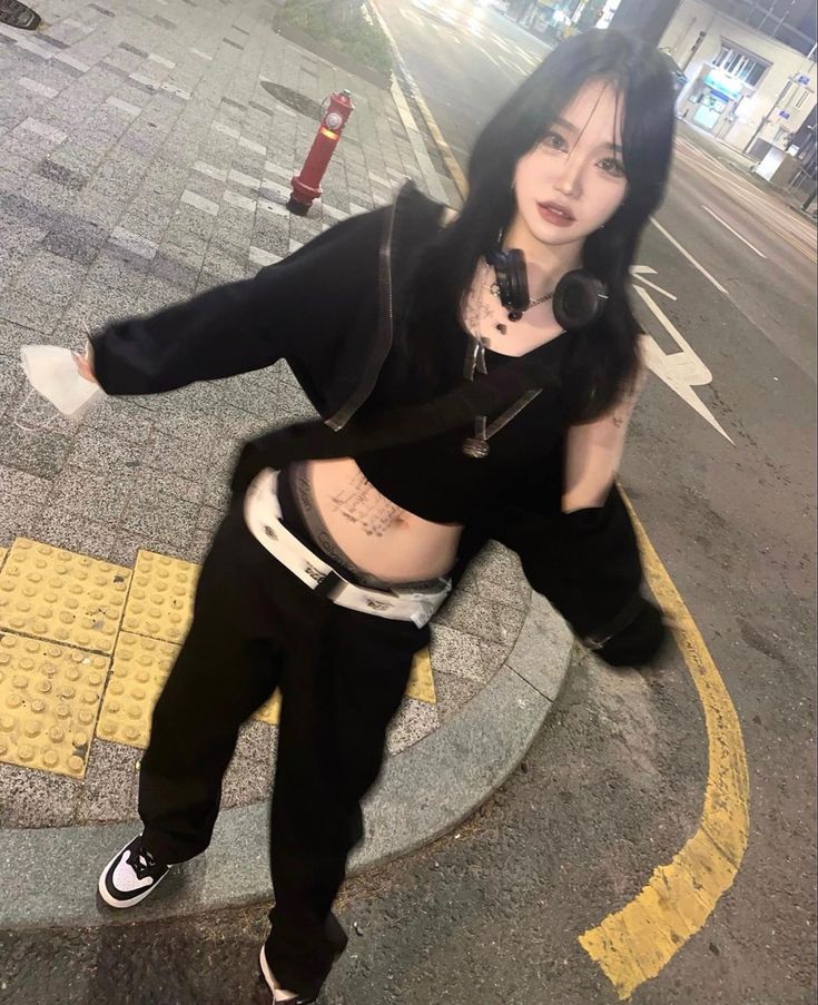 a woman is dancing on the street in black and white clothes with her hands behind her back