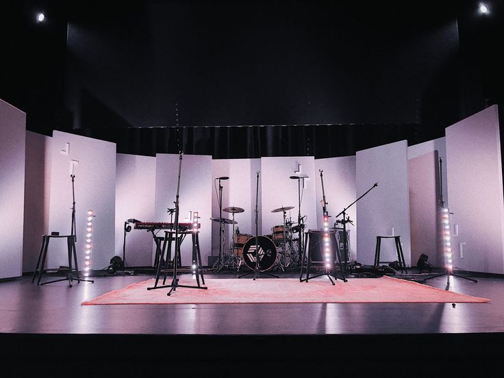 a stage set up for a musical performance with lights on the floor and drum stands