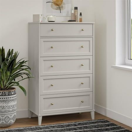 a white chest of drawers next to a potted plant