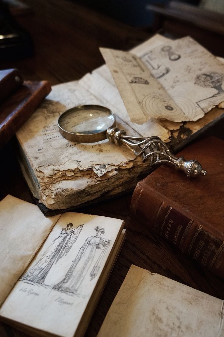 an old book and magnifying glass sitting on top of each other next to some books