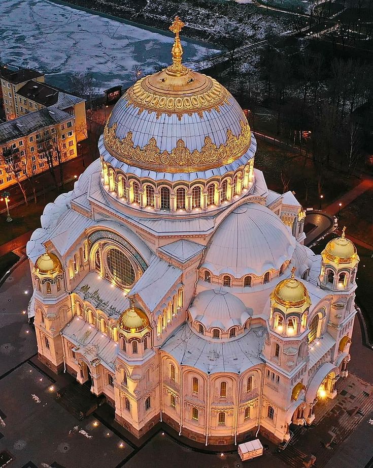 an aerial view of a large building lit up at night with lights on the top