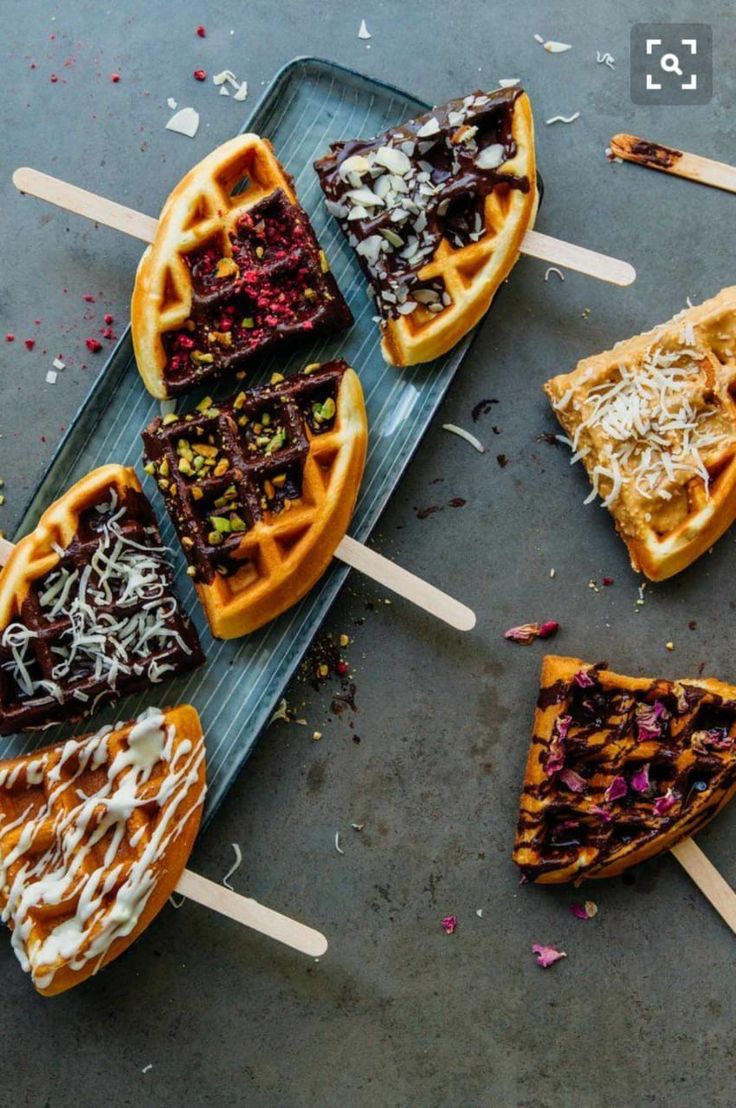 several waffles on sticks with toppings and sprinkles arranged around them