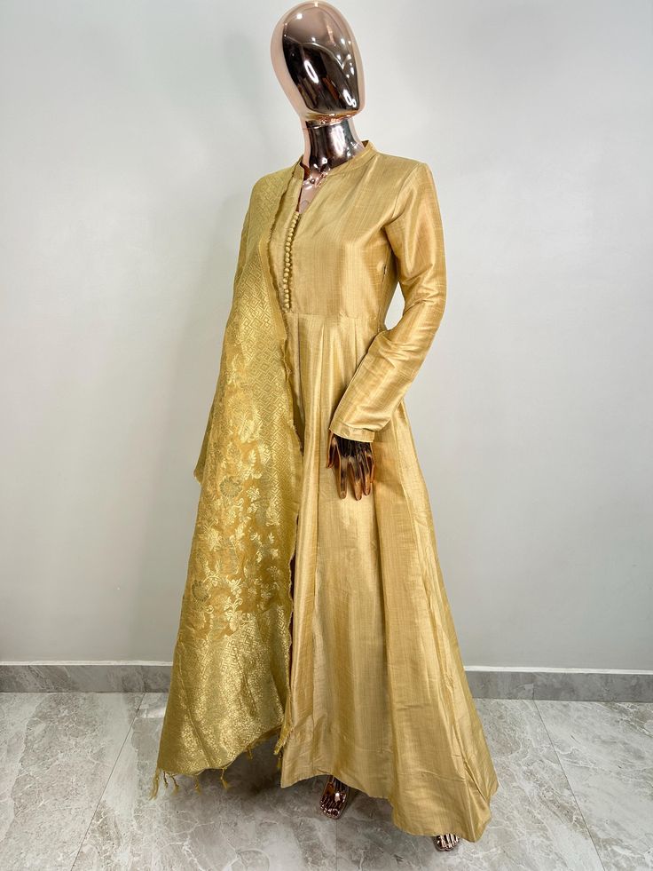 Gold Toned Solid Woven Cotton Woven Maxi Dress with Banarsi Silk Dupatta For Women Indian Wedding/Party Wear Gown  A-line/Anarkali Kurta With Dupatta This outfit is made with the finest  cotton of India.  The set contains : 1 maxi dress 1 dupatta Kurta: The gold toned solid Woven maxi dress features a mandarin collar with hook and eye closure. The anarkali kurta comes with an attached lining. The kurta measure till the ankle length and has flared hem.  Sleeve length :  Full Sleeves Dupatta :  Co Long Sleeve Slub Silk Anarkali Set For Festivals, Fitted Slub Silk Salwar Kameez With Cutdana, Long Sleeve Slub Silk Dress With Zari Work, Bollywood Style Long Sleeve Slub Silk Dress, Gold Long Sleeve Slub Silk Kurta, Yellow Long Sleeve Anarkali Set For Transitional Season, Transitional Yellow Anarkali Set With Long Sleeves, Gold Anarkali Salwar Kameez, Transitional Yellow Long Sleeve Anarkali Set