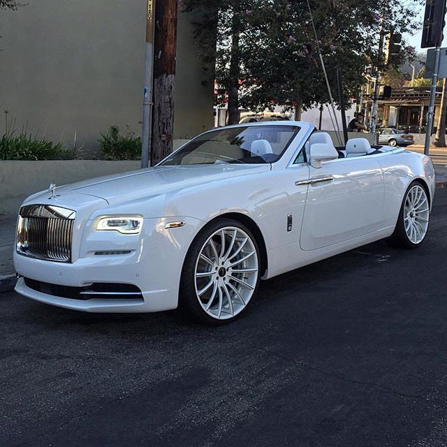 a white rolls royce parked on the side of the road in front of a building